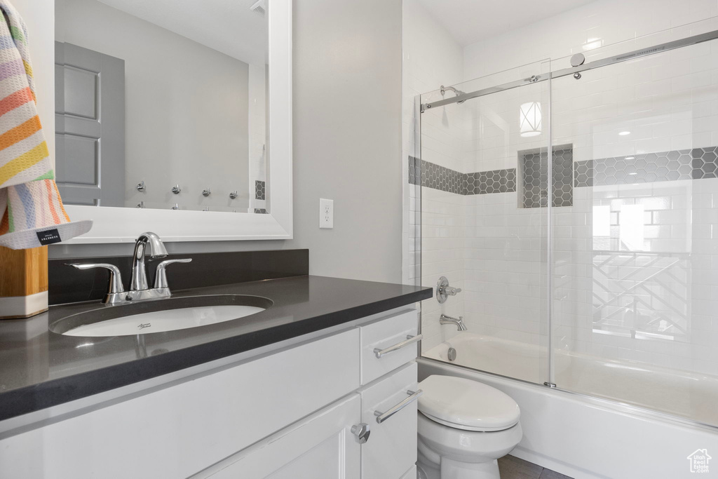 Full bathroom featuring combined bath / shower with glass door, vanity, and toilet