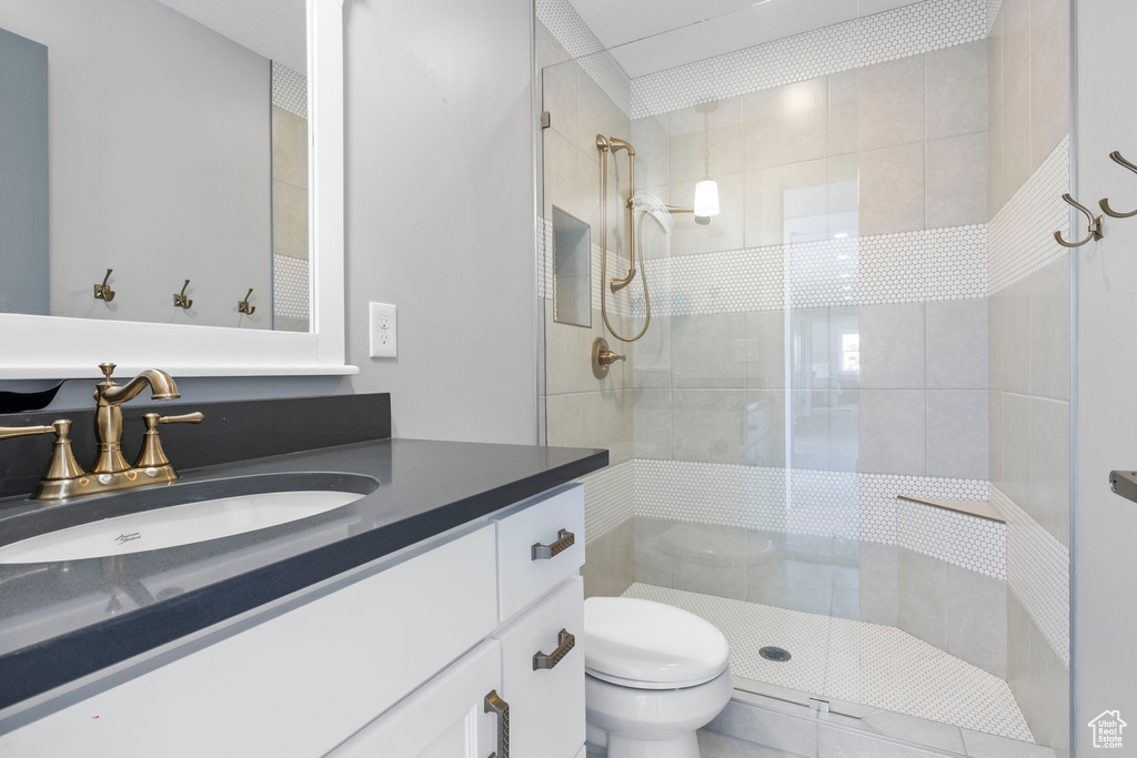 Bathroom with a shower with shower door, vanity, and toilet