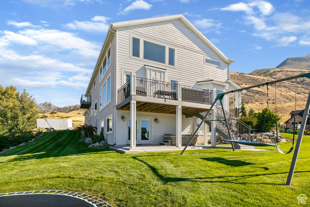 Back of house featuring a deck with mountain view, a yard, and a patio area