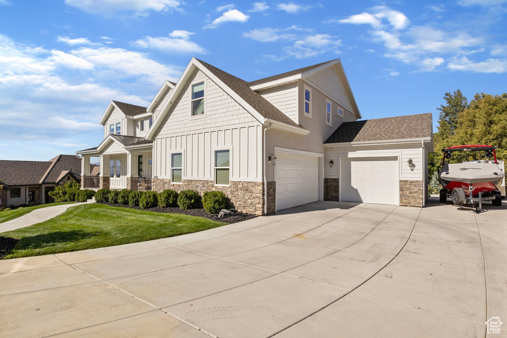 View of front of property with a front lawn, a porch, and a garage