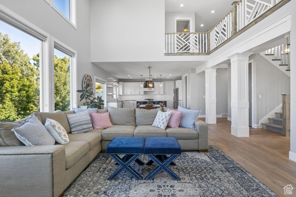 Living room featuring wood-type flooring, a high ceiling, and ornate columns