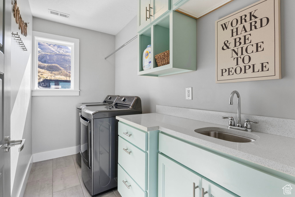 Laundry room featuring cabinets, independent washer and dryer, light tile patterned flooring, and sink