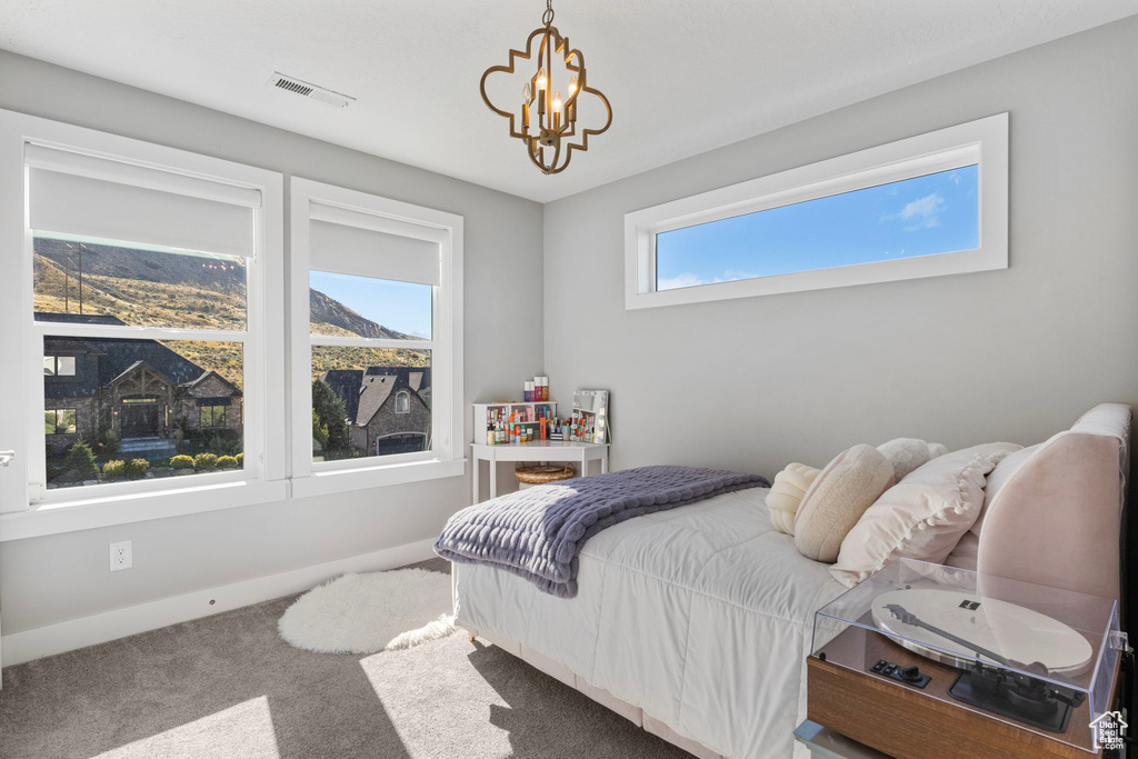 Carpeted bedroom featuring a notable chandelier