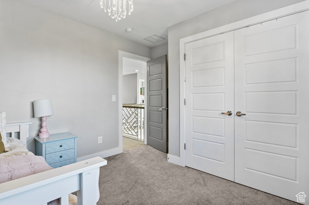 Carpeted bedroom with an inviting chandelier and a closet