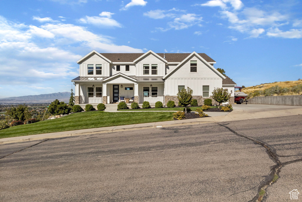 View of front of property featuring a front lawn, a mountain view, and covered porch