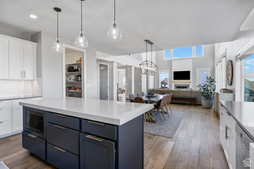 Kitchen featuring white cabinets, hanging light fixtures, tasteful backsplash, appliances with stainless steel finishes, and dark hardwood / wood-style flooring