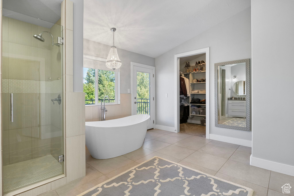 Bathroom with independent shower and bath, tile patterned flooring, vaulted ceiling, and an inviting chandelier