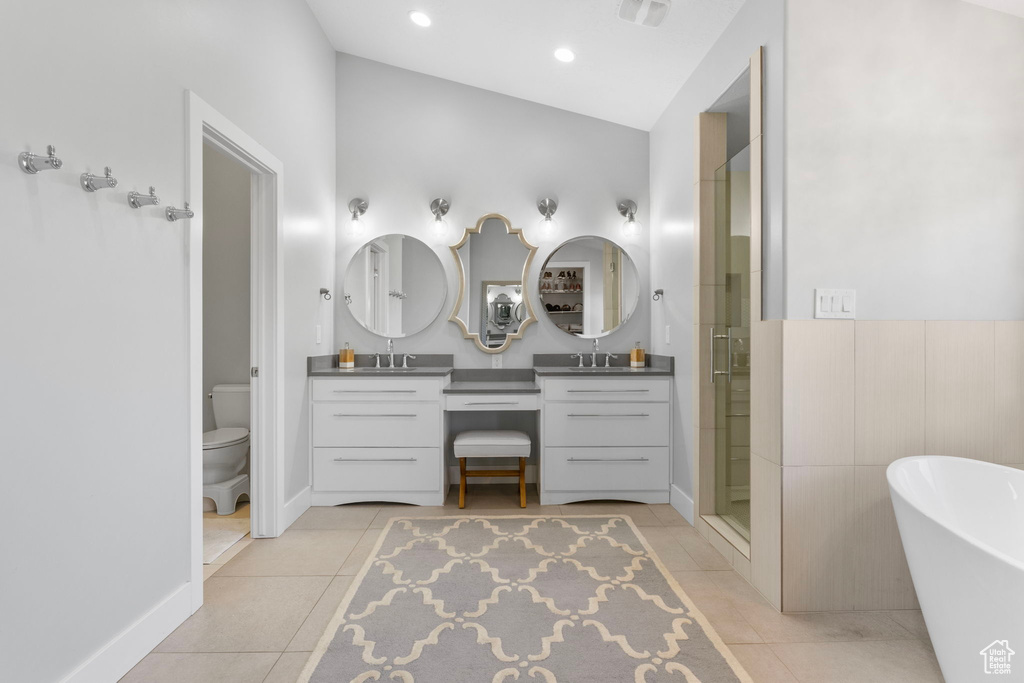 Full bathroom with vanity, tile patterned flooring, vaulted ceiling, plus walk in shower, and toilet