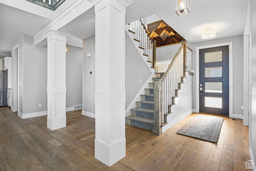 Foyer featuring decorative columns and hardwood / wood-style floors