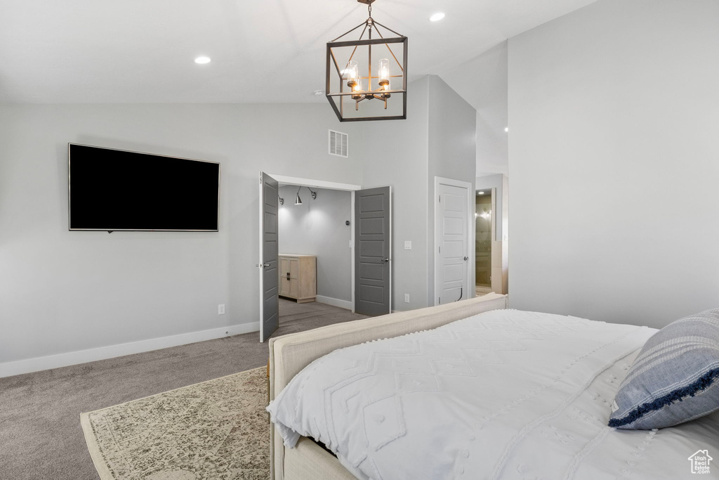 Bedroom featuring light carpet, lofted ceiling, and ensuite bathroom