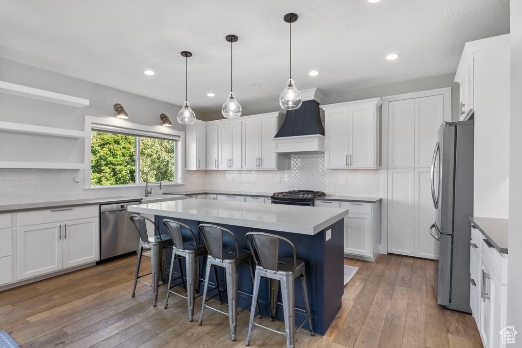 Kitchen featuring white cabinets, stainless steel appliances, light wood-type flooring, and a center island