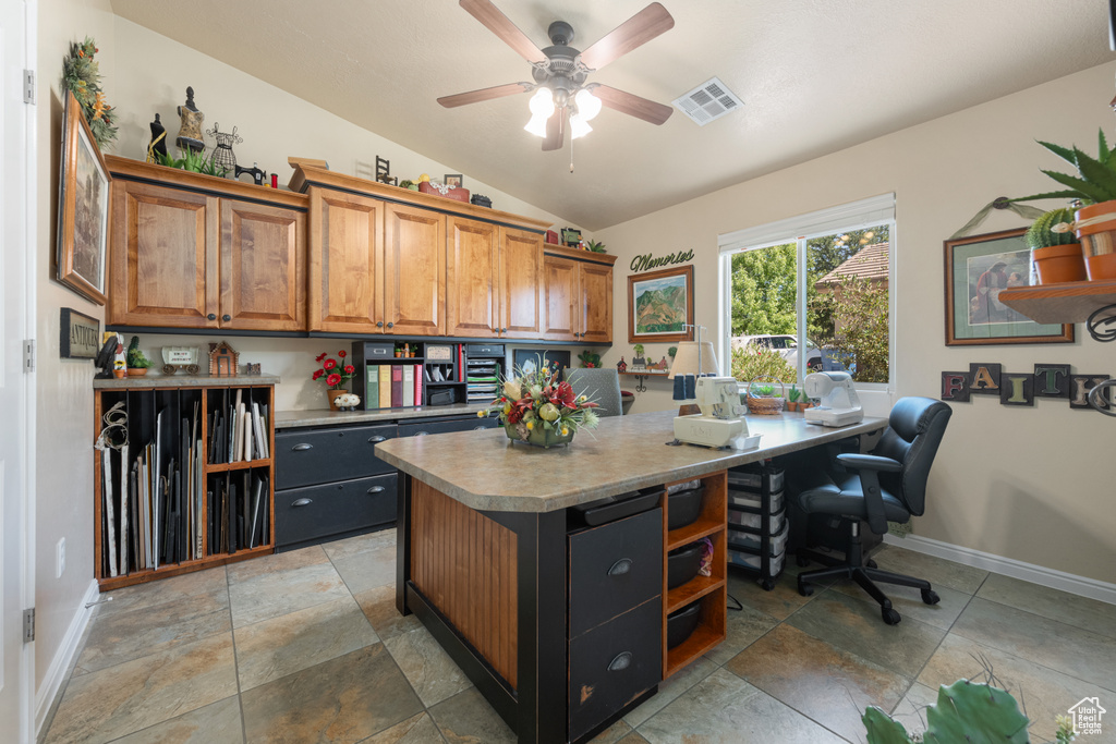 Office space with built in desk, ceiling fan, and vaulted ceiling