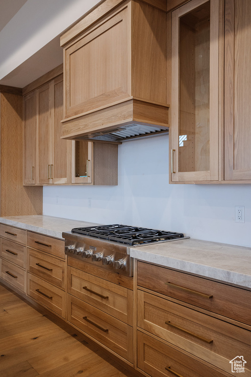 Kitchen with light hardwood / wood-style floors, stainless steel gas cooktop, light brown cabinets, and custom exhaust hood