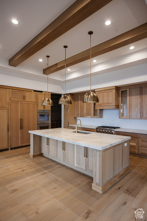 Kitchen featuring light wood-type flooring, beamed ceiling, a spacious island, and sink