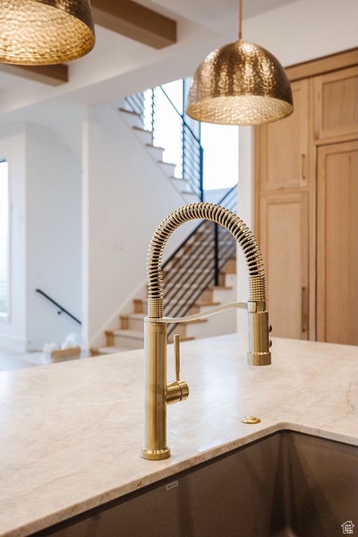 Room details with light stone countertops, decorative light fixtures, and sink