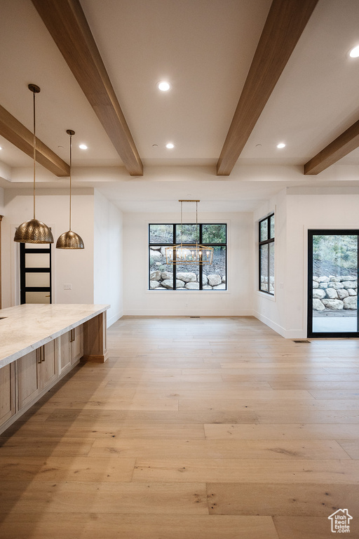 Interior space featuring plenty of natural light, beamed ceiling, and light hardwood / wood-style flooring