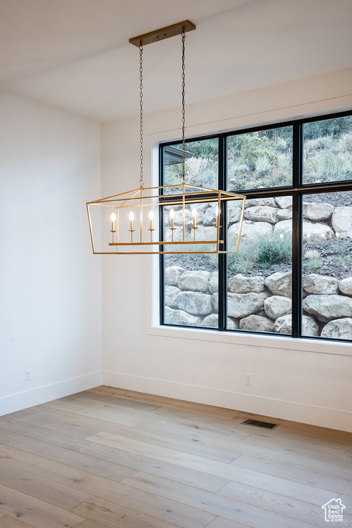 Interior space featuring a healthy amount of sunlight, an inviting chandelier, and light hardwood / wood-style flooring