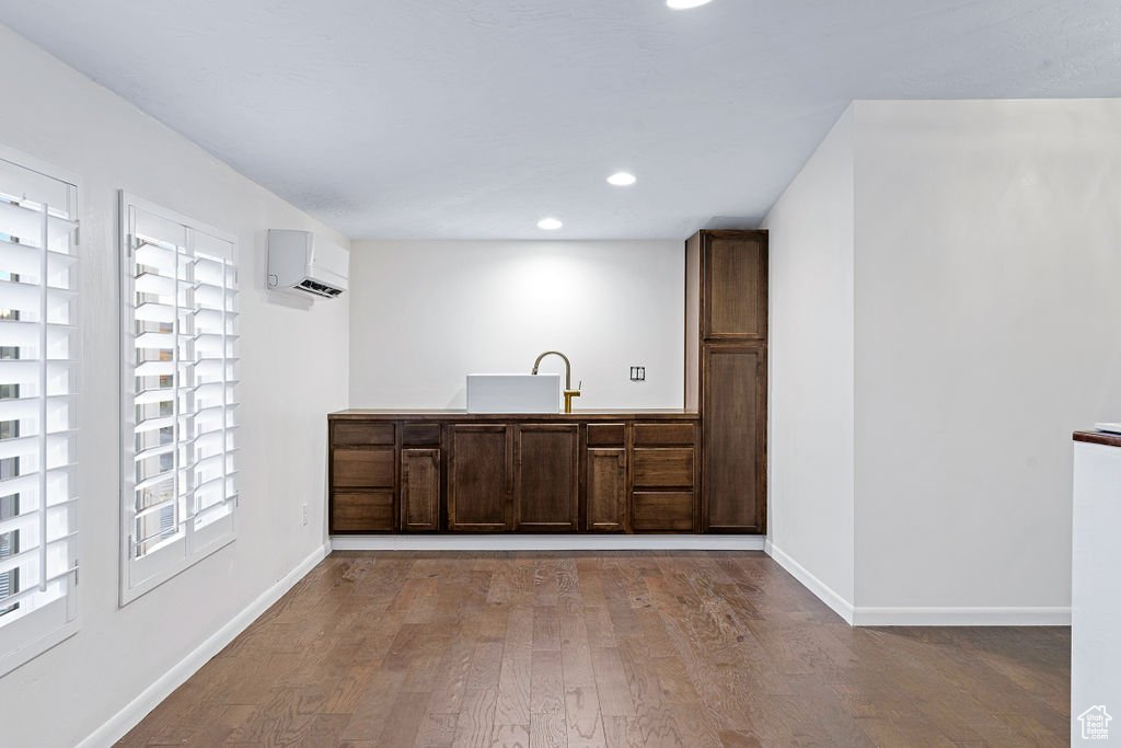 Interior space with light wood-type flooring, dark brown cabinetry, an AC wall unit, and sink