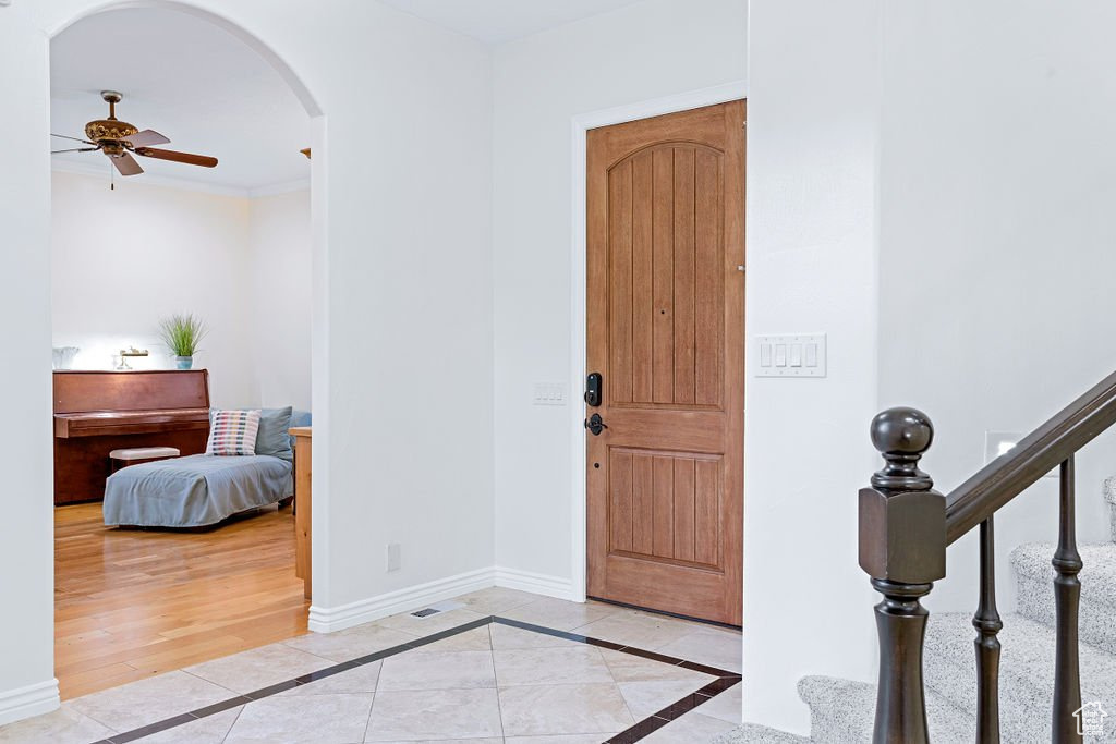 Entrance foyer with crown molding, light hardwood / wood-style floors, and ceiling fan