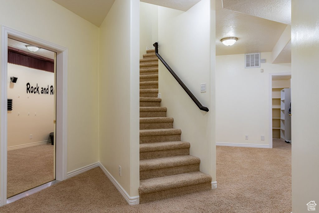 Staircase with a textured ceiling and carpet flooring