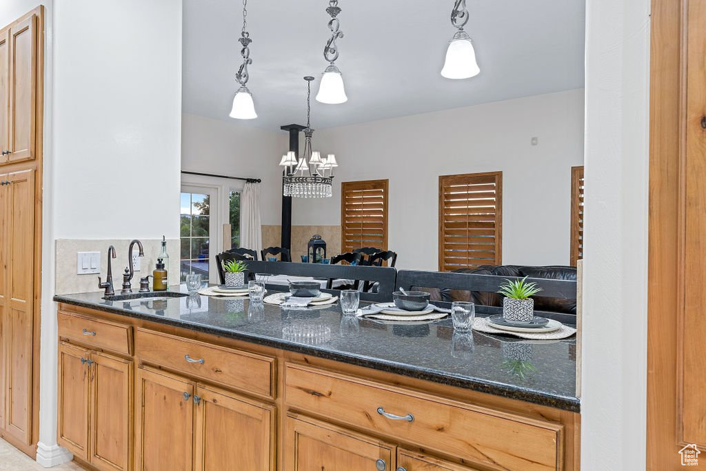 Kitchen featuring dark stone counters, hanging light fixtures, sink, and a notable chandelier