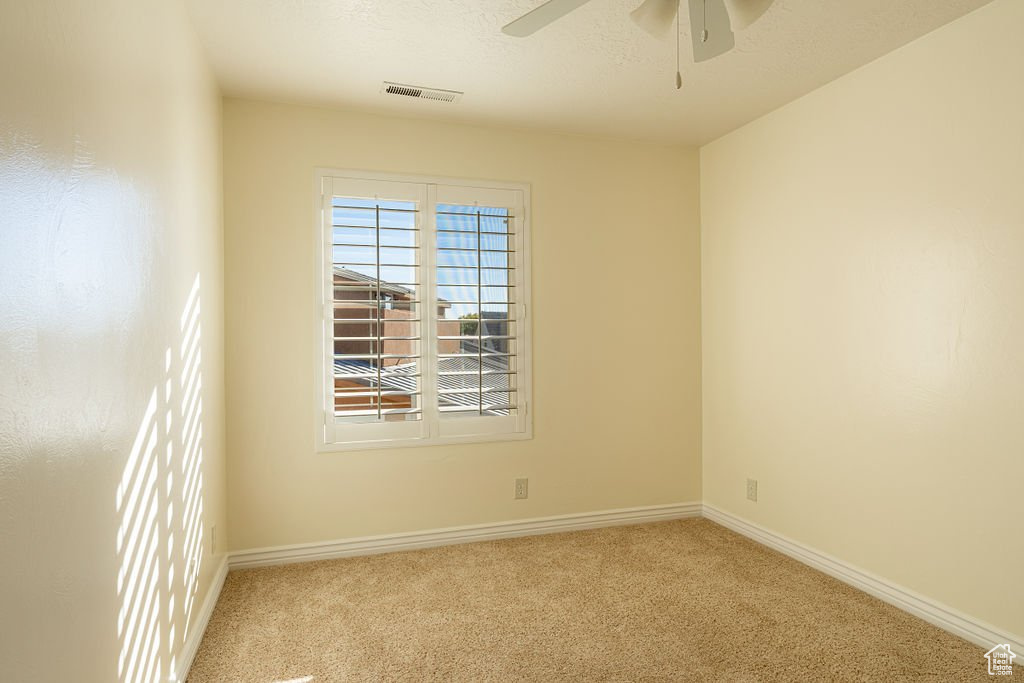 Carpeted spare room featuring ceiling fan and a textured ceiling