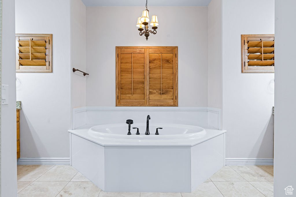 Bathroom featuring a notable chandelier, a bathtub, and tile patterned flooring