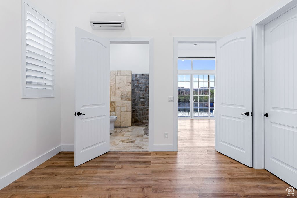 Interior space featuring wood-type flooring, ensuite bath, and a wall mounted air conditioner