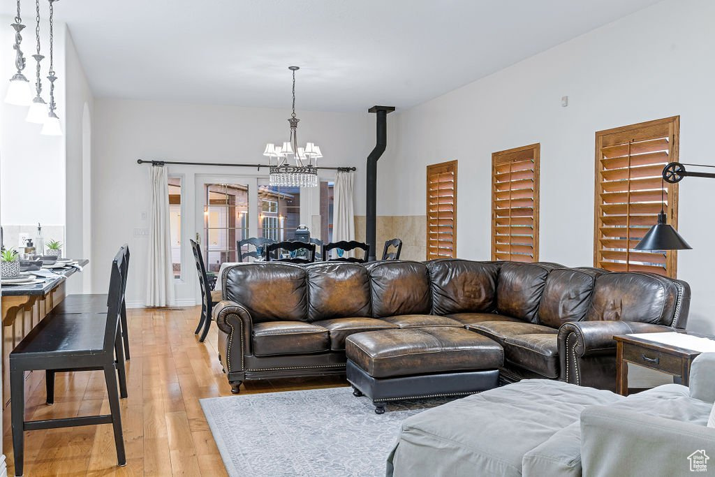 Living room with a notable chandelier, a wood stove, light hardwood / wood-style floors, and plenty of natural light