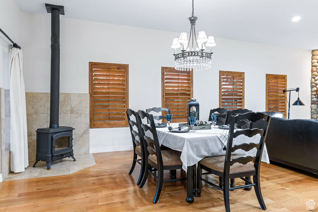 Dining area with an inviting chandelier, light wood-type flooring, and a wood stove