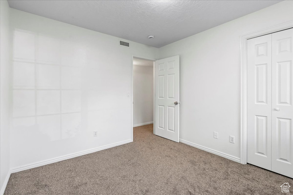 Unfurnished bedroom with a textured ceiling, carpet, and a closet