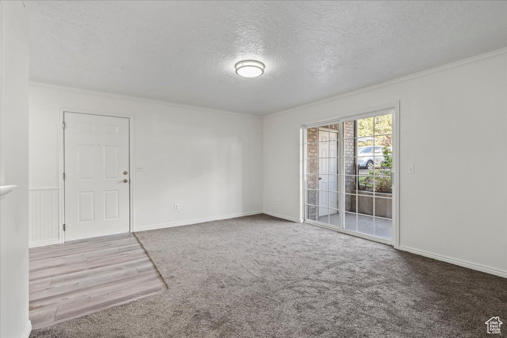 Empty room with a textured ceiling, crown molding, and hardwood / wood-style flooring