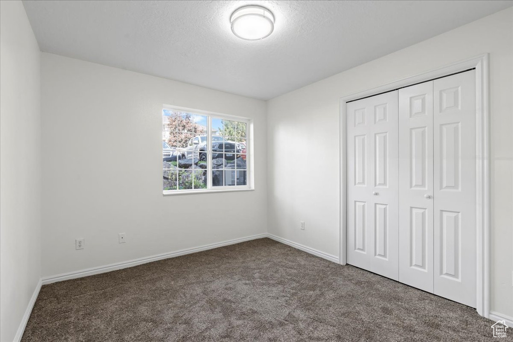 Unfurnished bedroom with a textured ceiling, a closet, and carpet