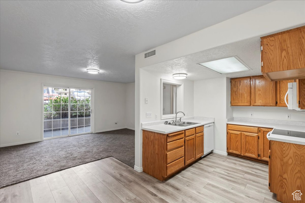 Kitchen with a textured ceiling, light hardwood / wood-style floors, sink, and white dishwasher