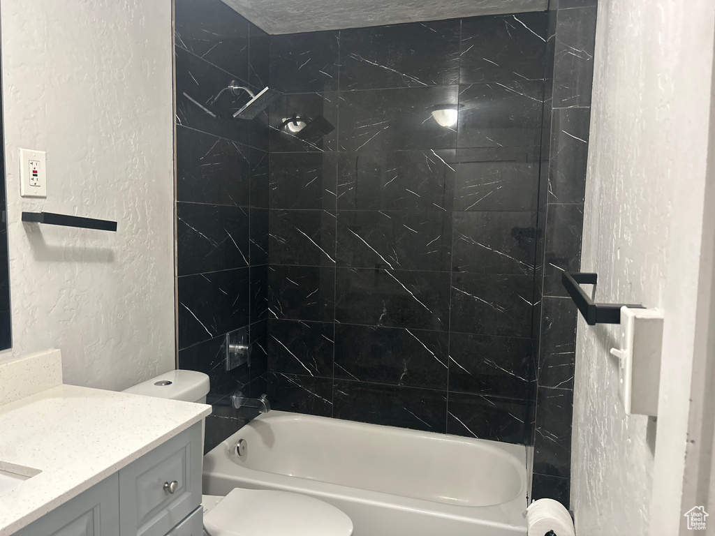 Full bathroom with a textured ceiling, vanity, toilet, and tiled shower / bath