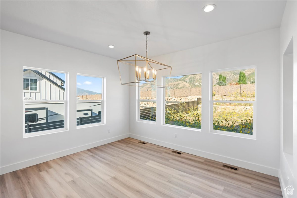 Unfurnished dining area with a notable chandelier and light hardwood / wood-style flooring