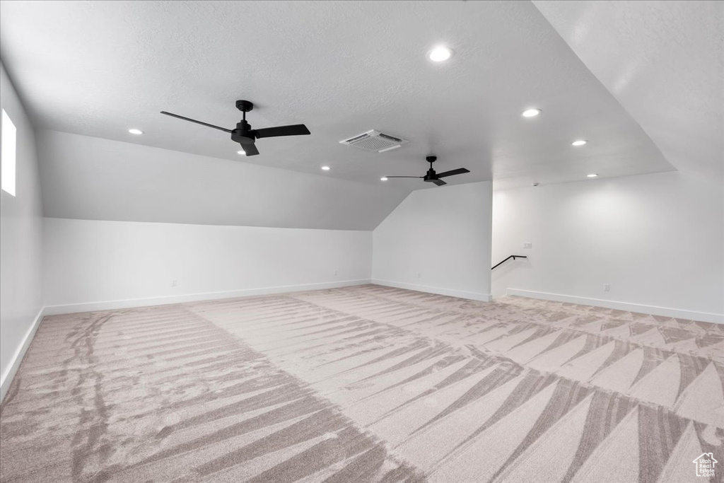 Bonus room featuring ceiling fan, light carpet, and vaulted ceiling