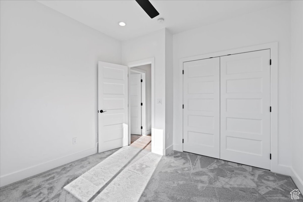 Bedroom with ceiling fan, light colored carpet, and a closet