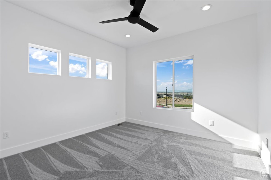 Spare room featuring carpet and ceiling fan