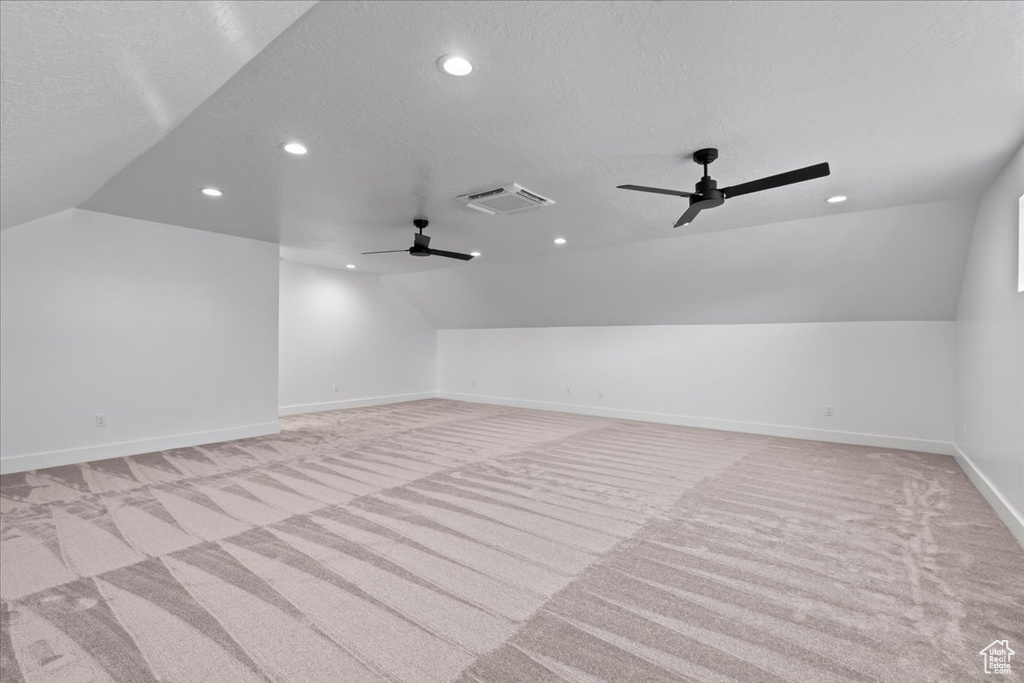 Additional living space featuring ceiling fan, light colored carpet, a textured ceiling, and vaulted ceiling