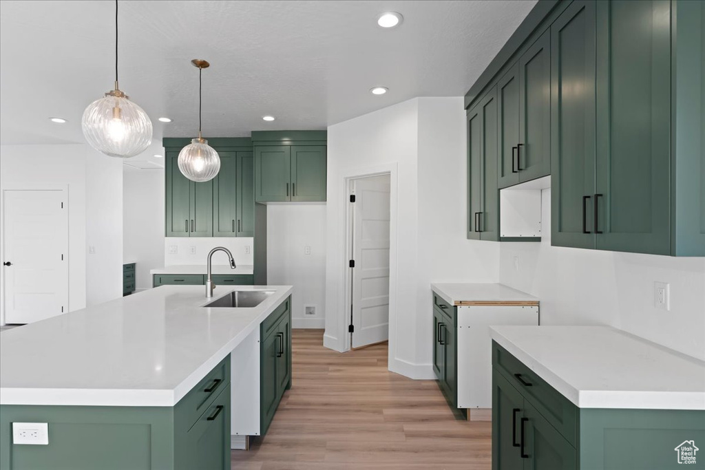 Kitchen featuring light hardwood / wood-style flooring, an island with sink, decorative light fixtures, and sink