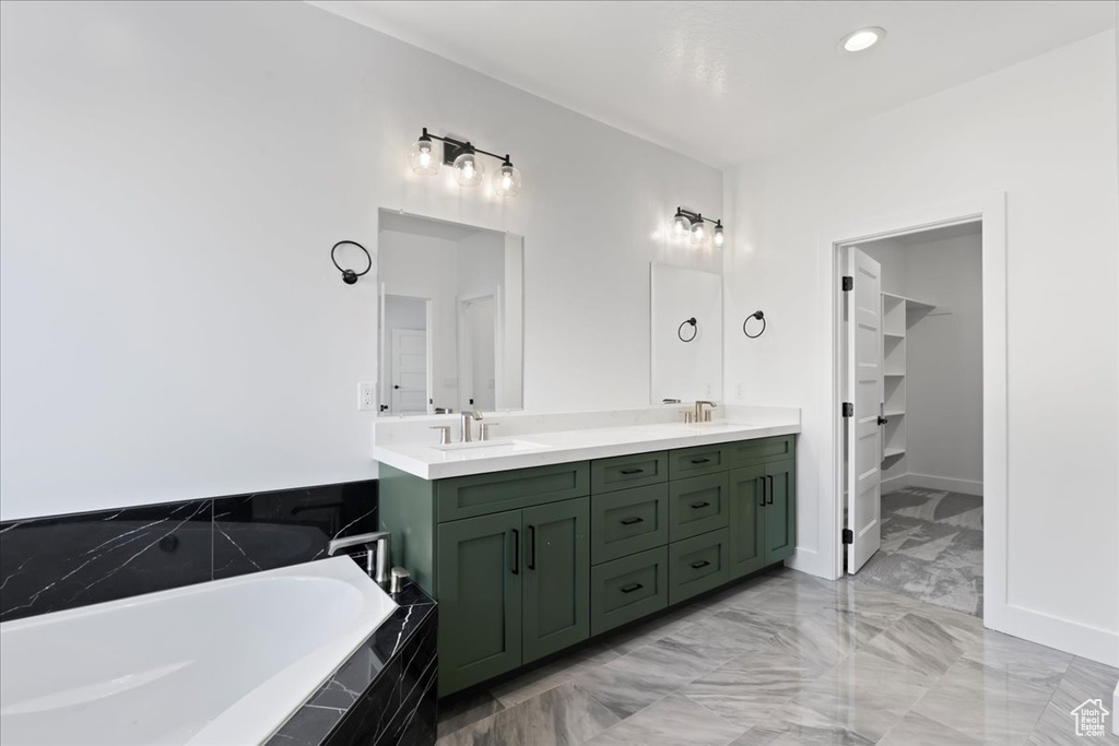 Bathroom featuring tiled tub and vanity