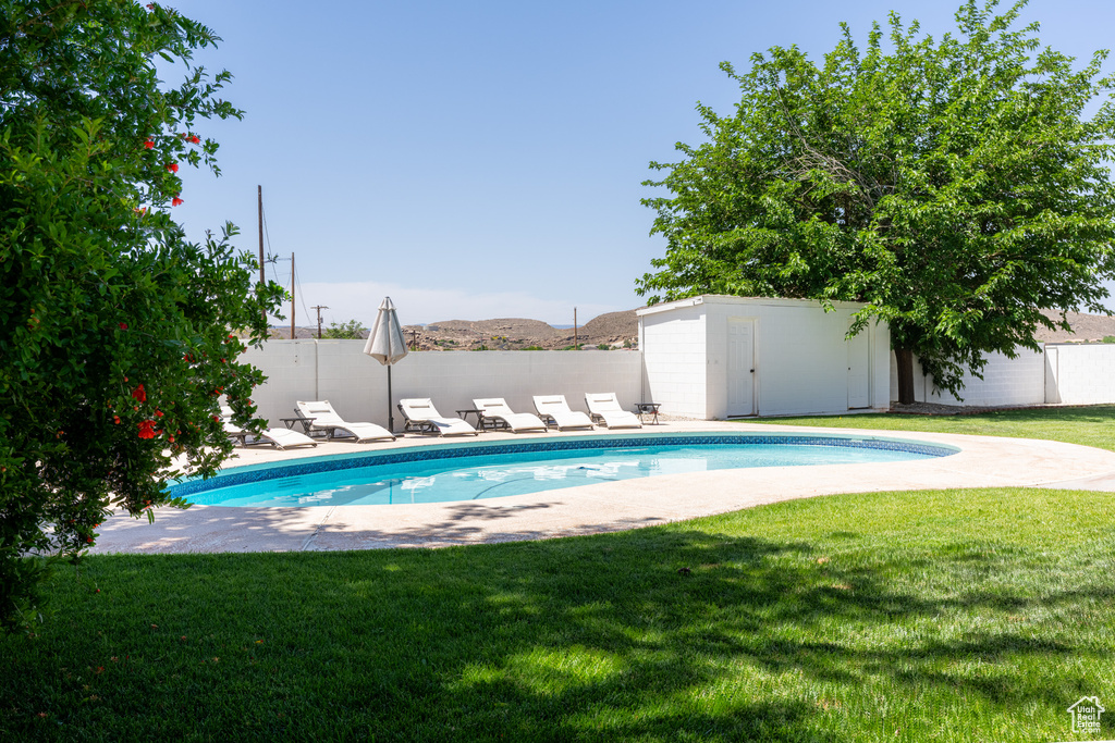 View of swimming pool with a lawn and a storage unit