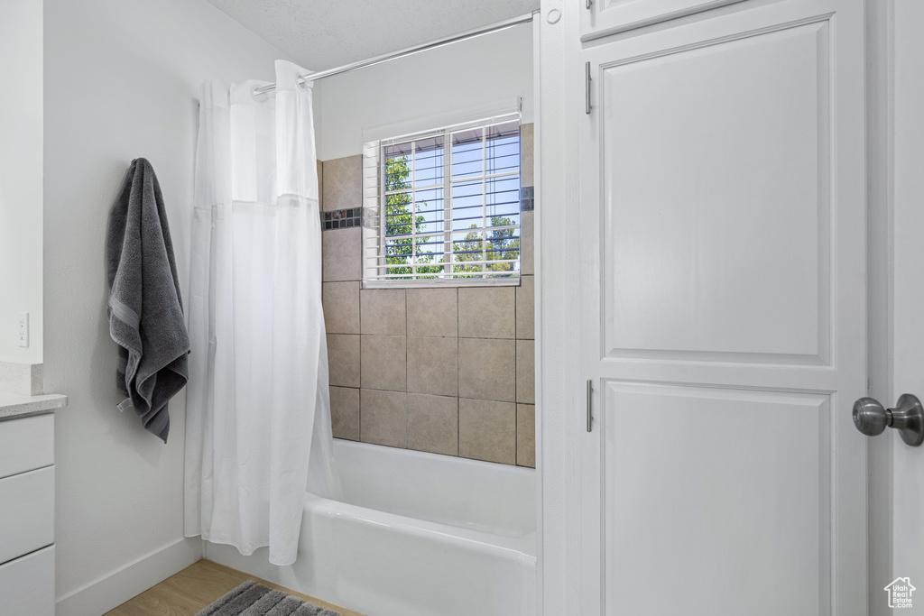 Bathroom featuring shower / bath combo with shower curtain, hardwood / wood-style floors, and vanity