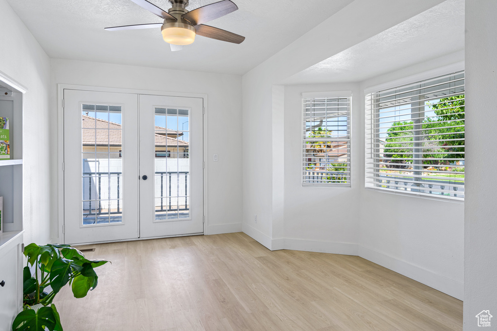 Doorway with french doors, a textured ceiling, light hardwood / wood-style flooring, and ceiling fan