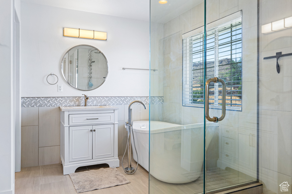 Bathroom with independent shower and bath, vanity, tile walls, and tile patterned flooring