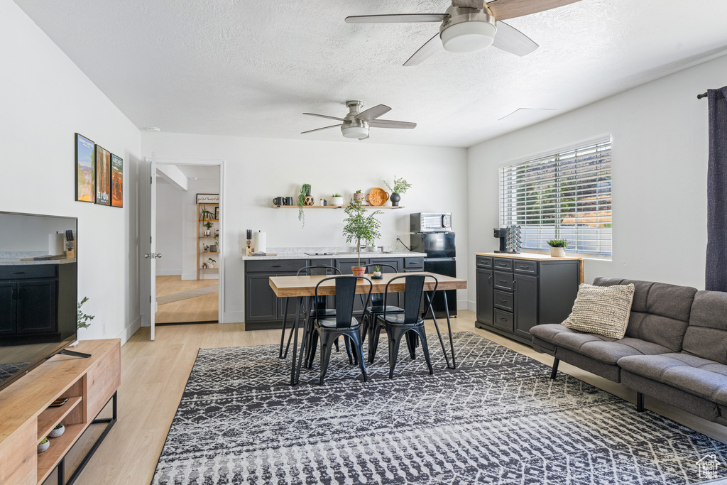 Dining space with light wood-type flooring, ceiling fan, and a textured ceiling