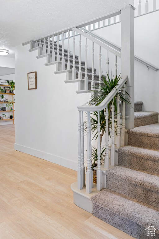 Stairs with a textured ceiling and hardwood / wood-style floors