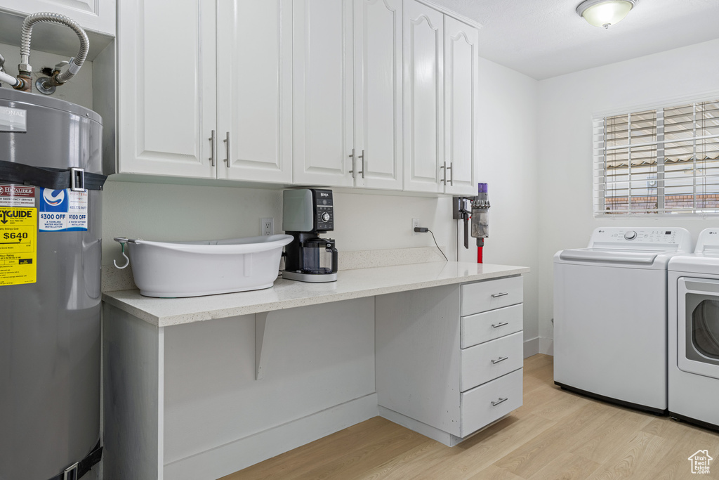 Washroom featuring cabinets, light wood-type flooring, strapped water heater, and washing machine and dryer