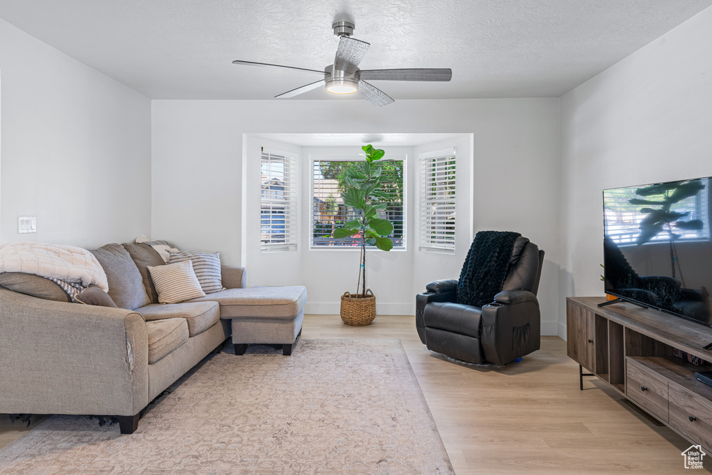 Living room with light wood-type flooring, ceiling fan, and a textured ceiling